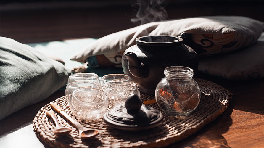 En bakke med krus og en tekande st�r p� gulvet ved siden af nogle puder.